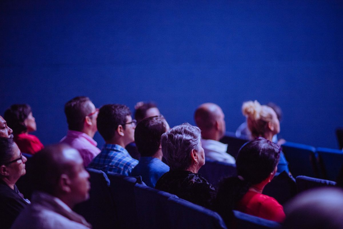 An attentive group of adults seated at an indoor conference, focusing on a presentation