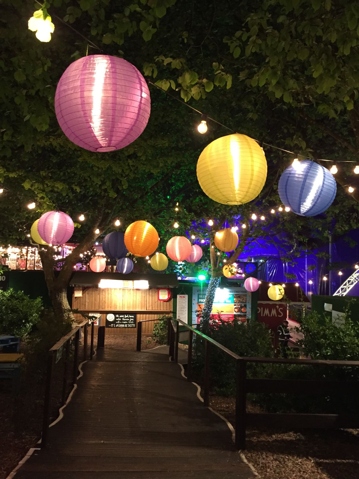 Vibrant paper lanterns hanging over an illuminated garden path at night